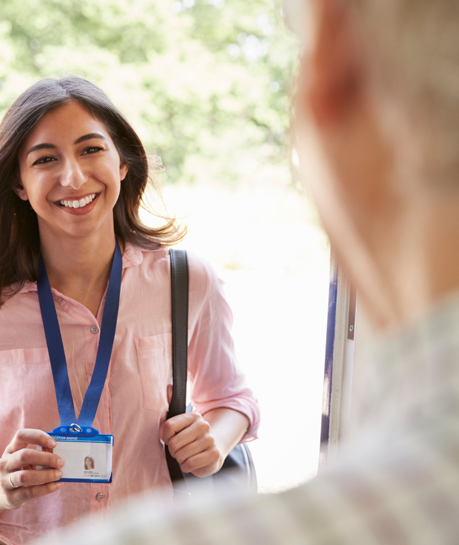 A caregiver showing her ID badge at the door