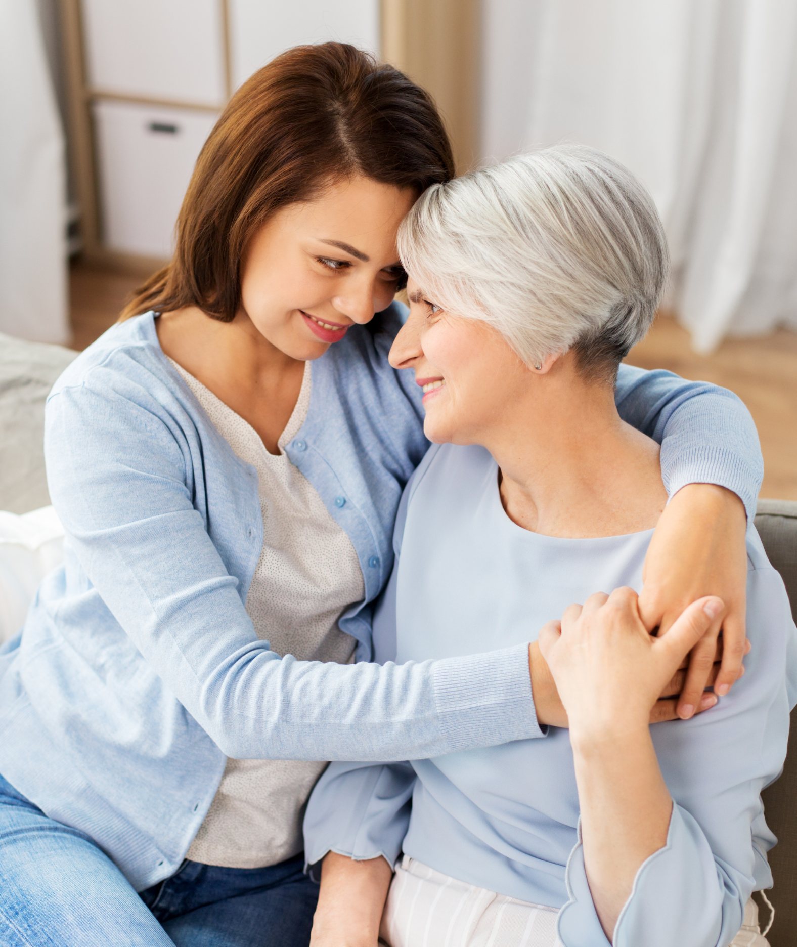 An adult daughter embracing her mother at home