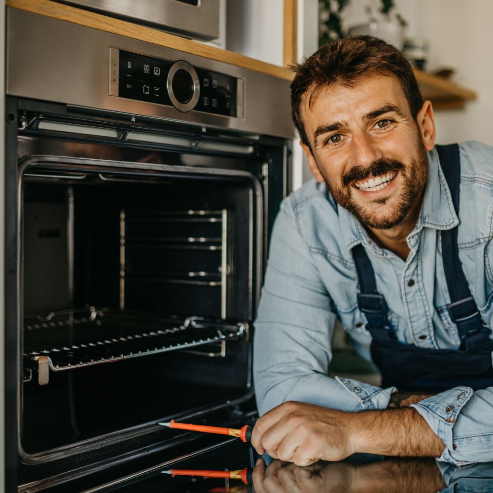 Smiling technician repairing an oven