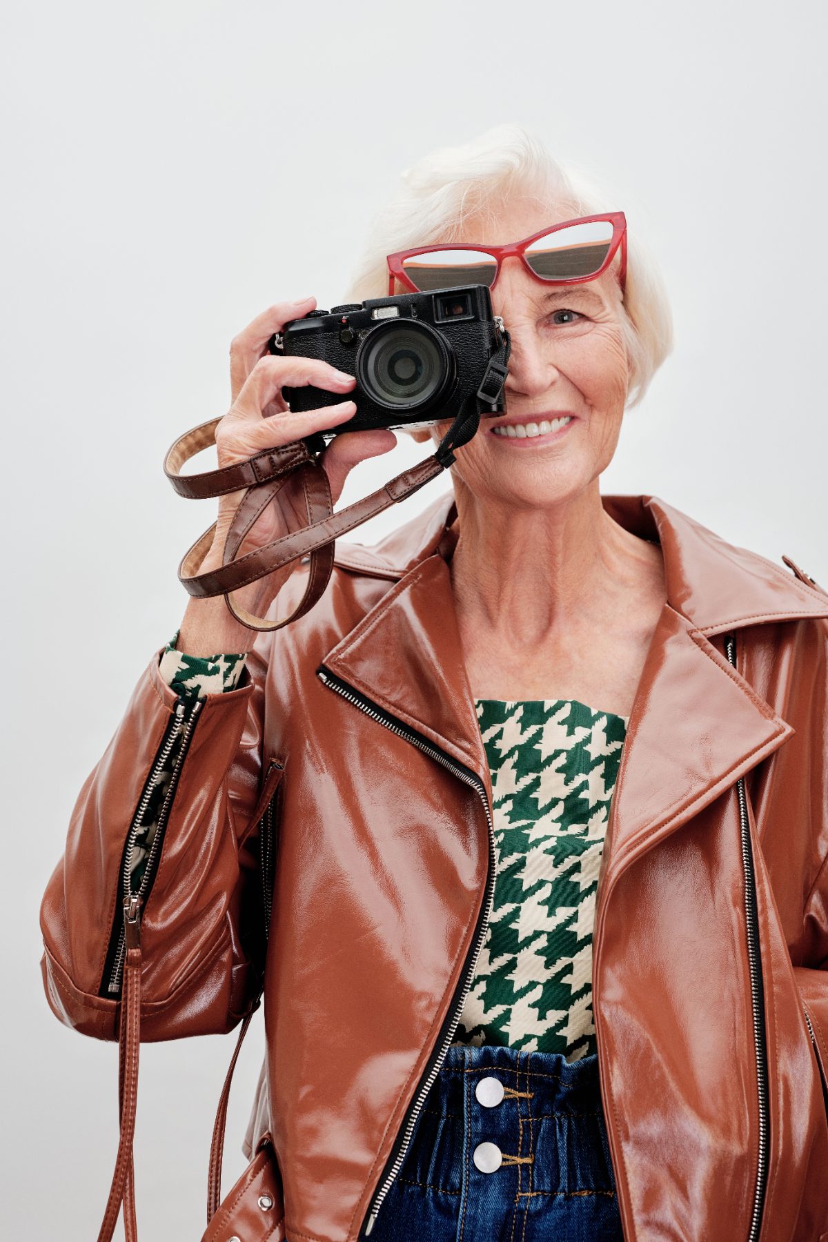 Woman in a leather jacket taking a photo with a vintage camera